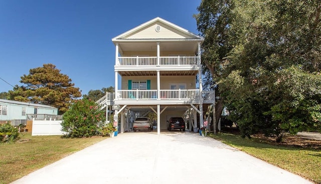 raised beach house featuring a carport, a front yard, and a balcony