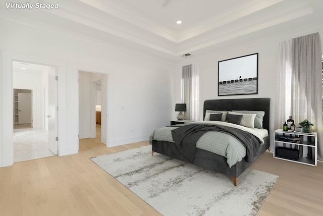 bedroom featuring a raised ceiling, wood-type flooring, and crown molding