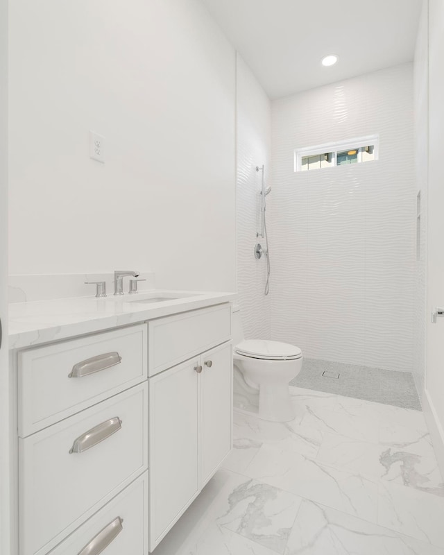 bathroom with toilet, vanity, and a tile shower