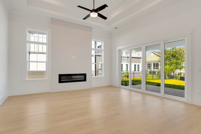 2313 Summersweet Ln, Myrtle Beach, SC 29579 - unfurnished living room with light wood-type flooring, a raised ceiling, a glass covered fireplace, and a ceiling fan