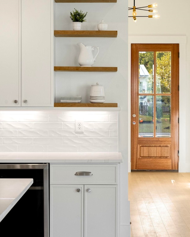 kitchen with tile counters, an inviting chandelier, white cabinetry, light hardwood / wood-style flooring, and wine cooler