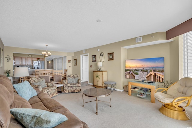 living room featuring an inviting chandelier, light carpet, and a textured ceiling