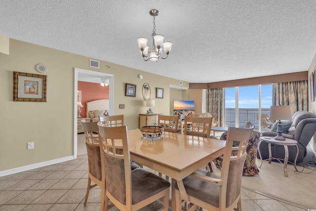 dining room with a textured ceiling, light tile patterned flooring, and ceiling fan with notable chandelier