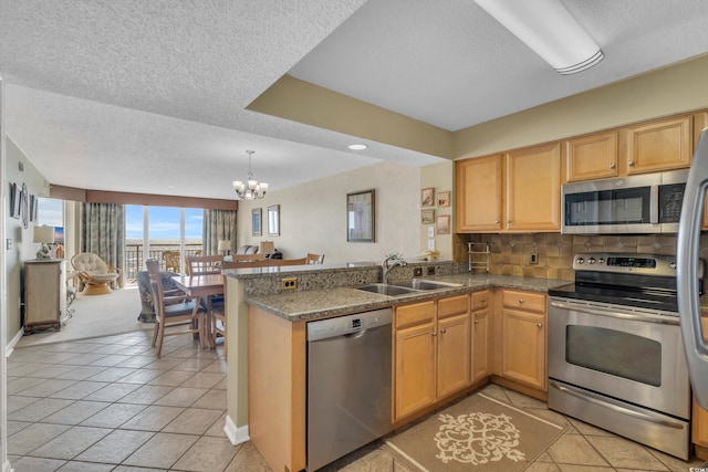 kitchen featuring stainless steel appliances, kitchen peninsula, sink, tasteful backsplash, and light tile patterned floors