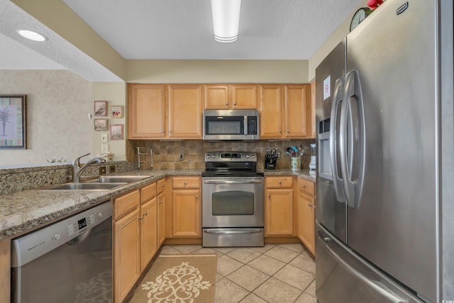 kitchen with decorative backsplash, sink, light tile patterned floors, light brown cabinets, and appliances with stainless steel finishes