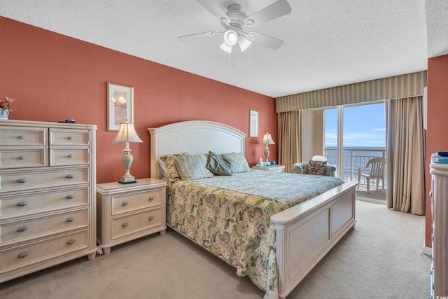 bedroom featuring light colored carpet, ceiling fan, a water view, and access to outside