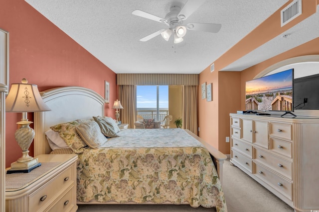 carpeted bedroom featuring ceiling fan and a textured ceiling