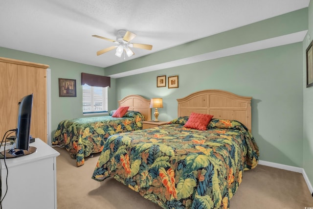 bedroom featuring a textured ceiling, light colored carpet, and ceiling fan