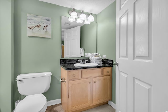 bathroom featuring toilet, vanity, and a textured ceiling