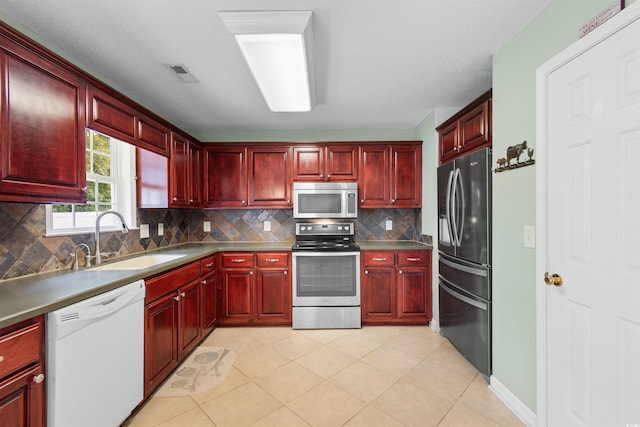 kitchen with light tile patterned floors, stainless steel appliances, tasteful backsplash, and sink