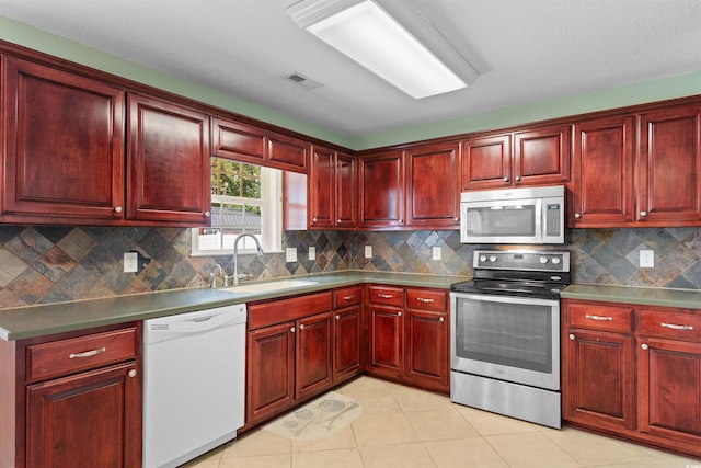 kitchen featuring decorative backsplash, sink, light tile patterned flooring, and appliances with stainless steel finishes