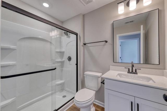 bathroom with toilet, vanity, hardwood / wood-style flooring, and a shower with door