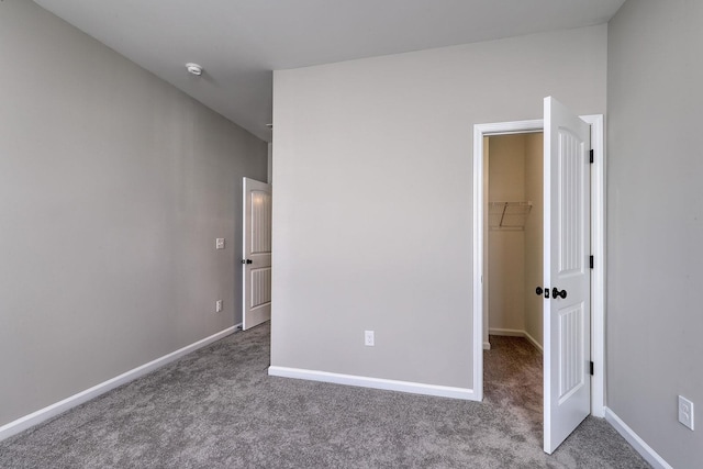 unfurnished bedroom with light colored carpet, a walk in closet, and a closet