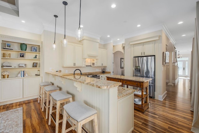 kitchen with dark hardwood / wood-style floors, kitchen peninsula, stainless steel appliances, pendant lighting, and light stone counters