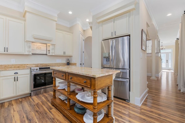 kitchen with appliances with stainless steel finishes, dark hardwood / wood-style floors, light stone counters, and ornamental molding