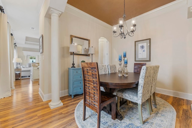 dining area featuring ornate columns, light hardwood / wood-style floors, crown molding, and an inviting chandelier