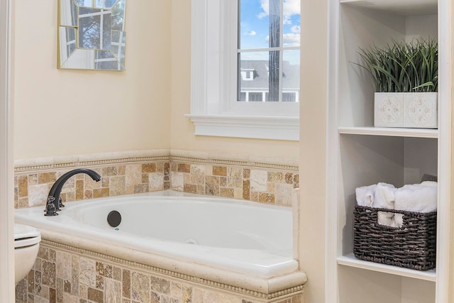 bathroom featuring toilet, a relaxing tiled tub, and a healthy amount of sunlight