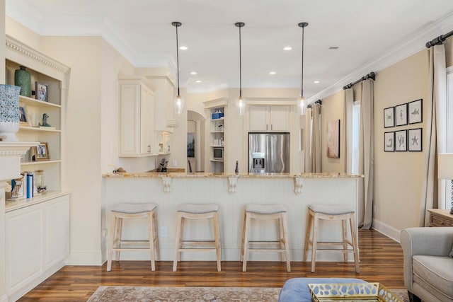 kitchen featuring kitchen peninsula, appliances with stainless steel finishes, dark wood-type flooring, pendant lighting, and light stone counters