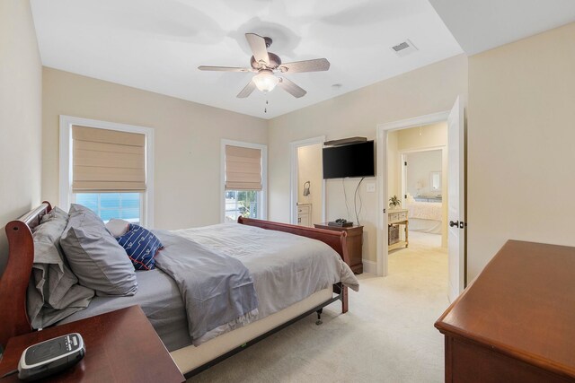 bedroom featuring connected bathroom, light colored carpet, and ceiling fan