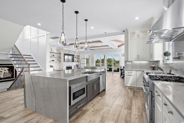 kitchen featuring white cabinets, wall chimney exhaust hood, a large island, light stone countertops, and appliances with stainless steel finishes