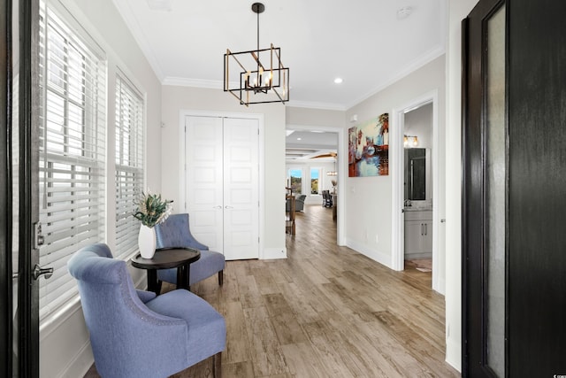 sitting room featuring a chandelier, light wood-type flooring, and ornamental molding