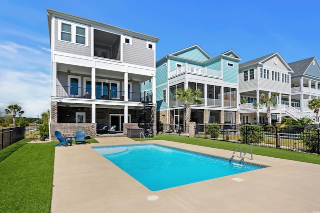 back of house featuring a fenced in pool, a patio area, a lawn, and a balcony