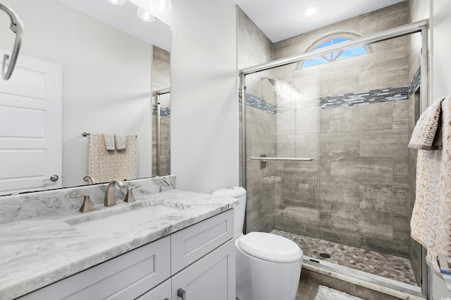 bathroom with toilet, vanity, and a shower with door