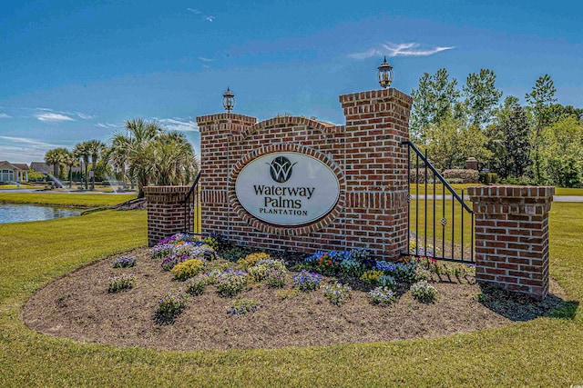 community sign with a water view and a lawn