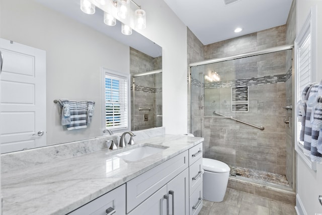 bathroom with toilet, vanity, and a shower with shower door