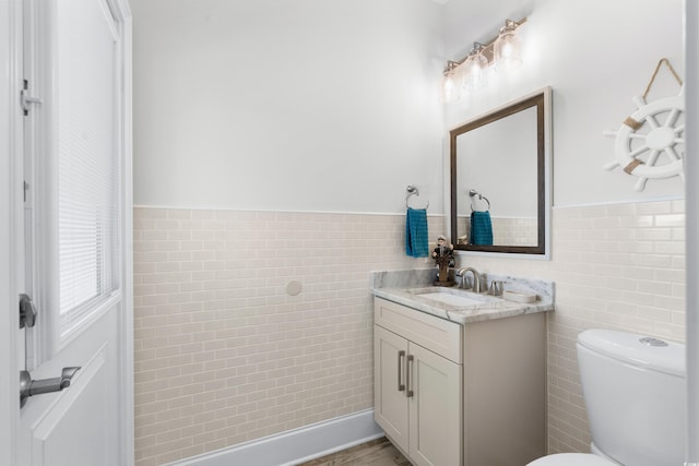 bathroom featuring tile walls, vanity, and toilet