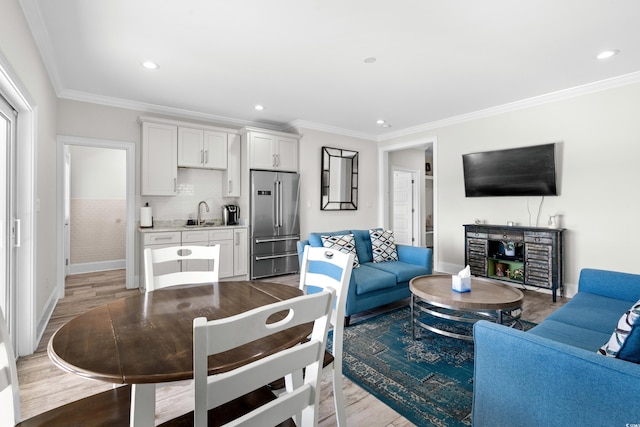 living room with light hardwood / wood-style floors, sink, and crown molding