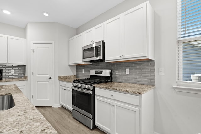 kitchen featuring white cabinets, appliances with stainless steel finishes, and light stone countertops