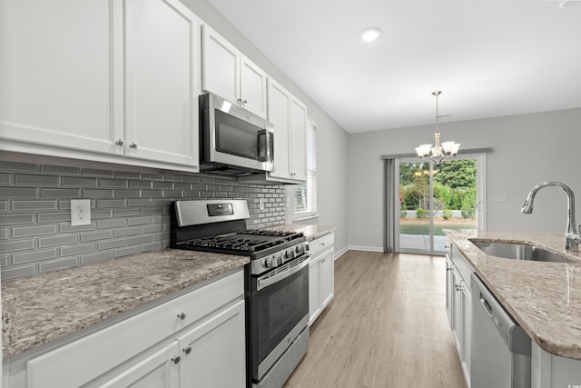 kitchen featuring stainless steel appliances, white cabinetry, sink, light stone counters, and light hardwood / wood-style flooring