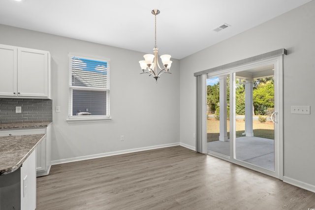 unfurnished dining area featuring hardwood / wood-style flooring and a chandelier