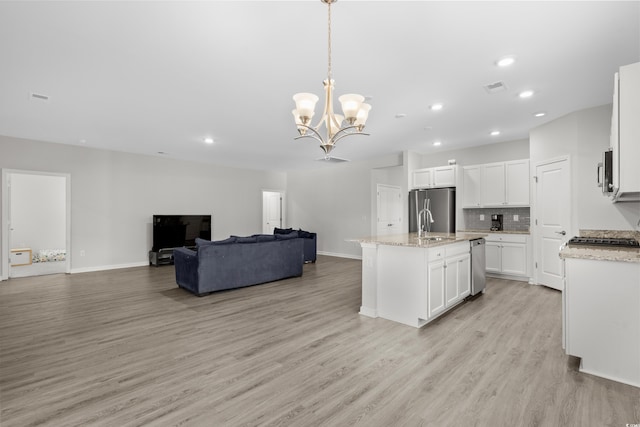 kitchen featuring appliances with stainless steel finishes, decorative light fixtures, an island with sink, light hardwood / wood-style flooring, and white cabinets