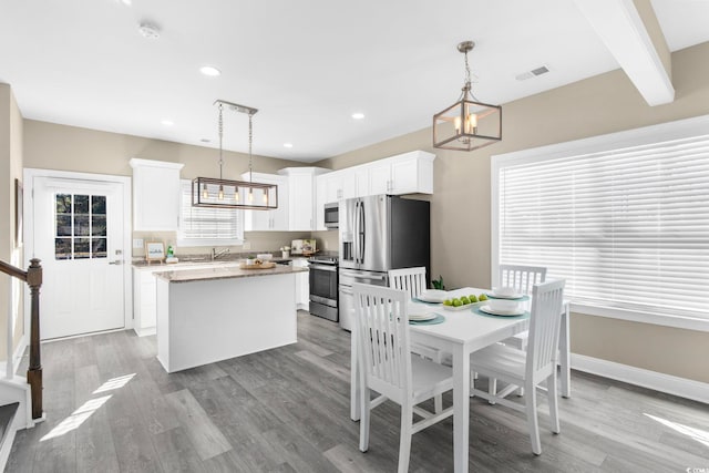 dining area with light hardwood / wood-style floors, a chandelier, sink, and beam ceiling