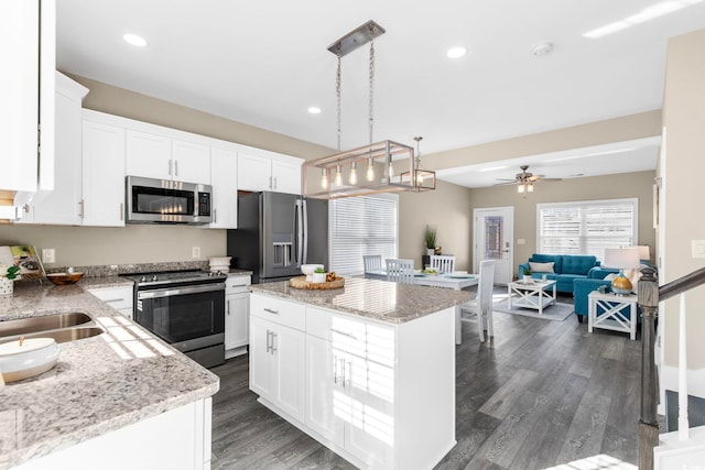 kitchen featuring white cabinetry, a center island, hanging light fixtures, and stainless steel appliances