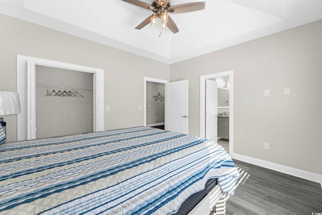 bedroom with ensuite bathroom, dark wood-type flooring, ceiling fan, and a closet