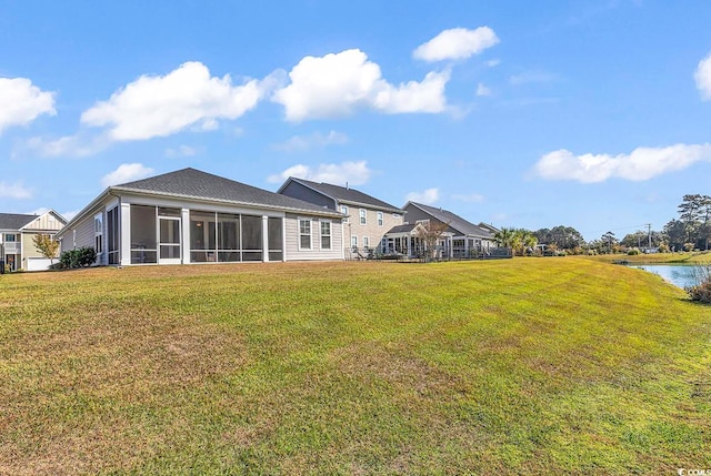 rear view of house with a sunroom, a lawn, and a water view