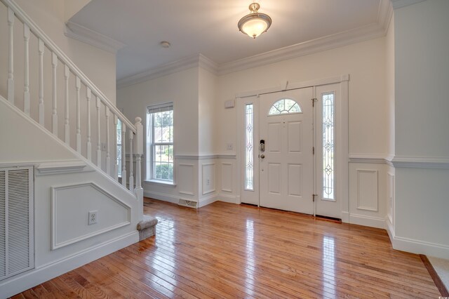 foyer with ornamental molding and light hardwood / wood-style flooring