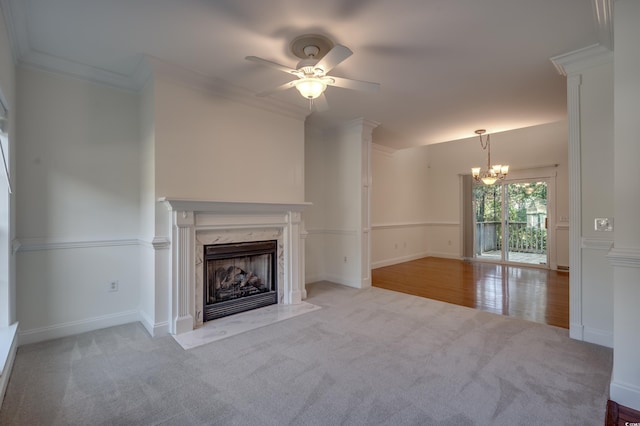 unfurnished living room with light colored carpet, ornamental molding, ceiling fan with notable chandelier, and a high end fireplace