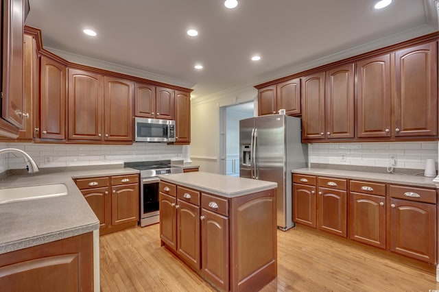 kitchen with light wood-type flooring, stainless steel appliances, crown molding, a kitchen island, and sink