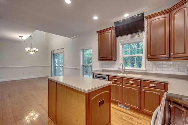 kitchen with sink, light wood-type flooring, a chandelier, a kitchen island, and pendant lighting