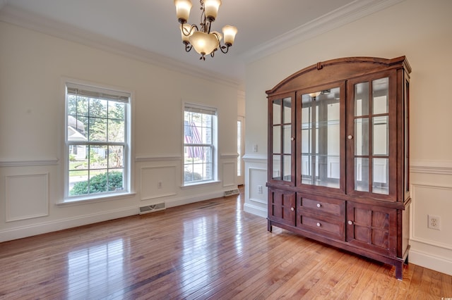 unfurnished dining area featuring light hardwood / wood-style floors, a notable chandelier, and ornamental molding