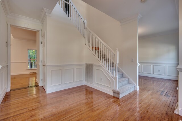 stairway featuring ornamental molding and wood-type flooring