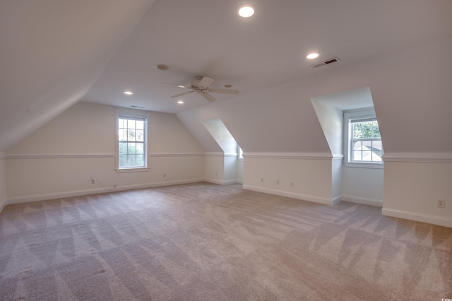 additional living space featuring lofted ceiling, ceiling fan, light colored carpet, and a healthy amount of sunlight