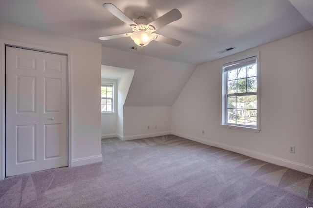 bonus room featuring plenty of natural light, lofted ceiling, light carpet, and ceiling fan