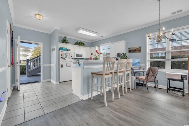 kitchen featuring light hardwood / wood-style floors, white cabinetry, white appliances, and pendant lighting