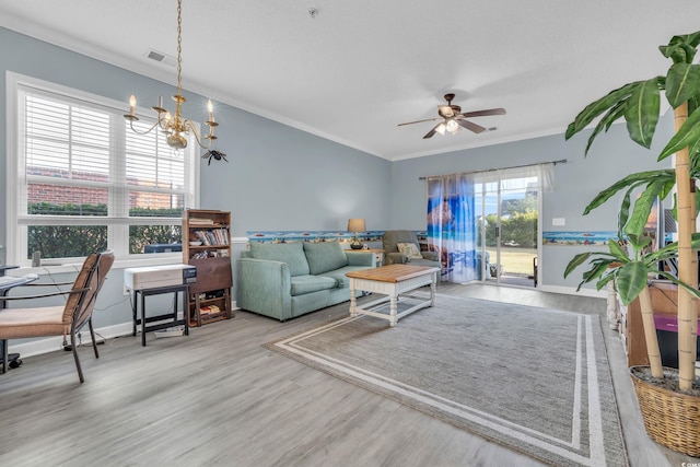 living room with ceiling fan with notable chandelier, hardwood / wood-style flooring, and crown molding