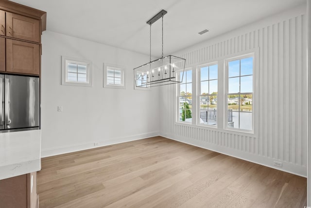 unfurnished dining area featuring a notable chandelier and light hardwood / wood-style floors